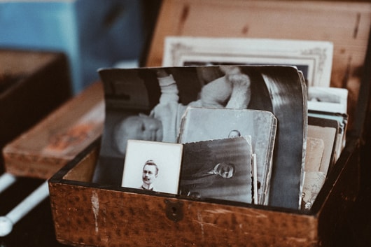 An small and antique looking wooden box with old, monochrome photographs in it.