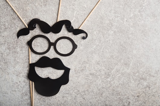 A face made up from cardboard requisites. Mustaches for eyebrows, a pair of glasses for outlining the eyes and a full beard to outline the mouth.