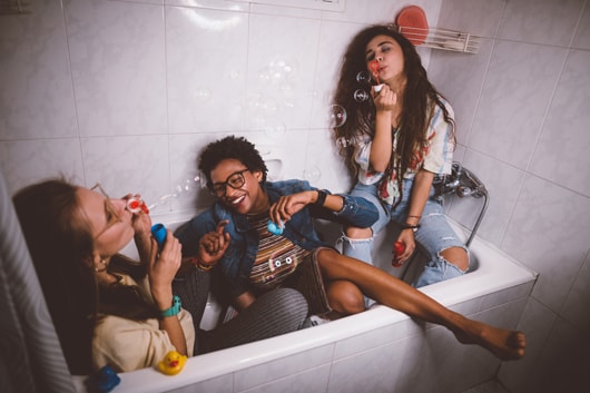 Party guests fooling around with soap bubbles in a bathtub.